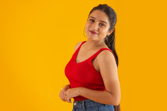 Portrait of teenage girl standing against yellow background
