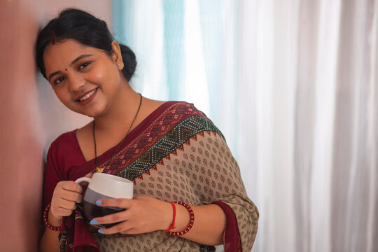Portrait of smiling woman looking at camera with a cup of tea at home
