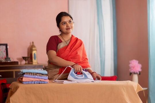 Portrait of a happy woman ironing clothes at home