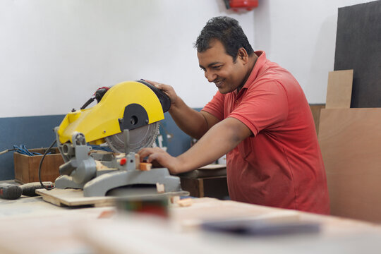 Young carpenter cutting a piece of wood with a hand circular saw