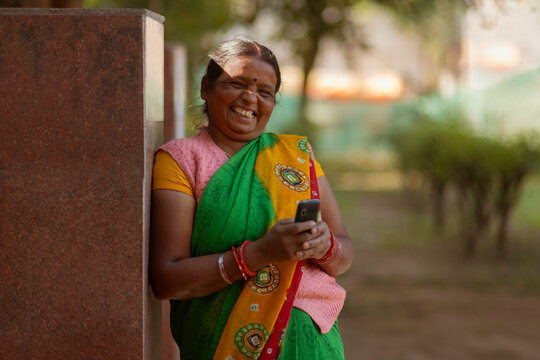 A house maid standing in the colony park using her mobile phone during her resting period 