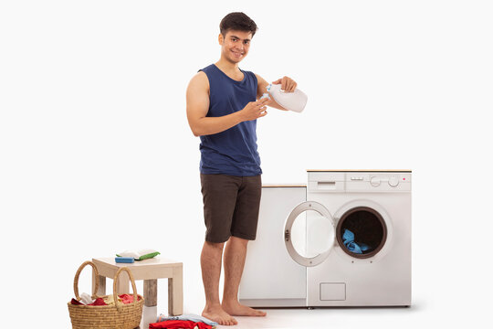 Portrait of young man pouring detergent 