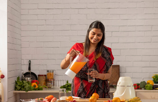 Cheerful woman pouring orage juice into a glass