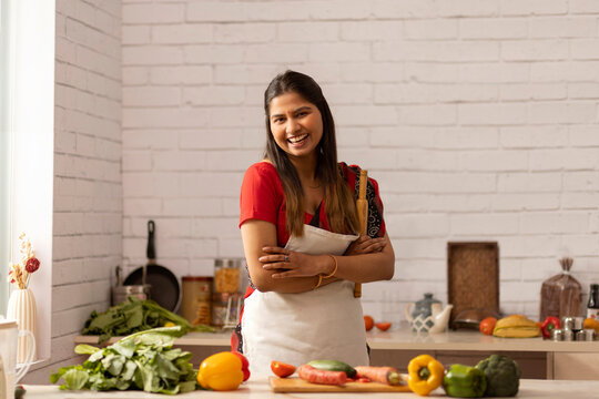 Smiling woman standing with rolling pin in kitchen