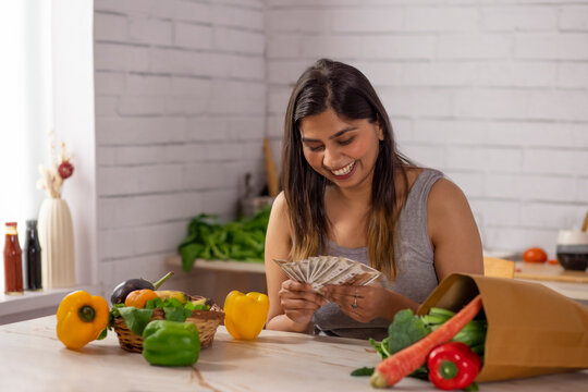 Woman counting money in kitchen after shopping