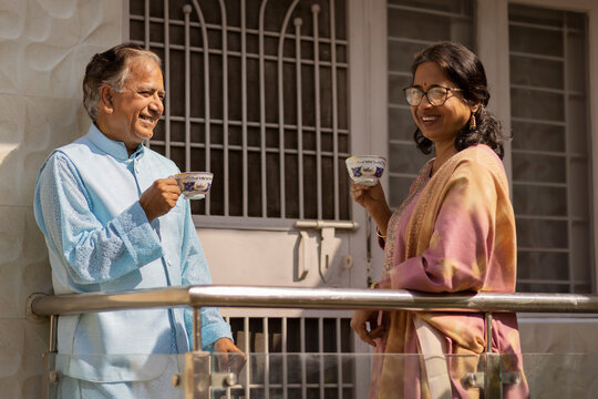 Mature couple having tea while standing in balcony