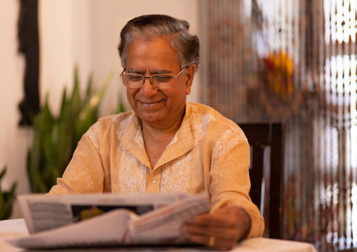 Portrait of senior man reading newspaper at home