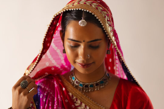 Close-up portrait of a cheerful Rajasthani young woman against white background