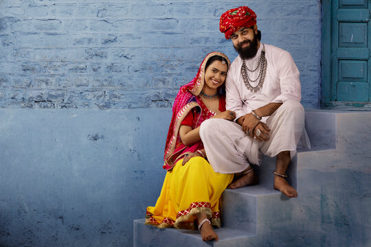 Rajasthani couple sitting on stairs sharing a light moment,as the husband plays ektara