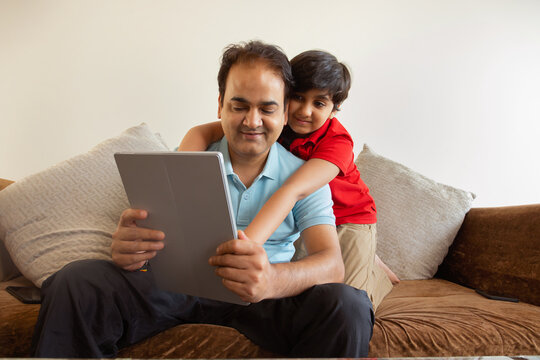 Father and son together using digital tablet in living room 