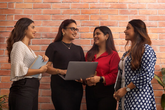 Group of businesswomen discussing project on laptop at office workstation