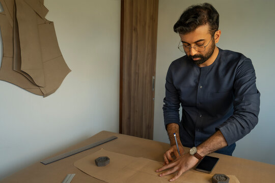 A male designer making patterns for a menswear collection in his studio 