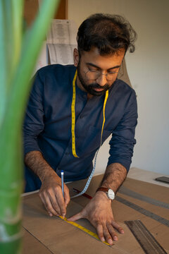 A male designer making patterns for a menswear collection in his studio 