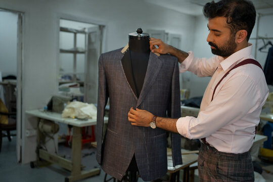 A bespoke tailor checking measurements on a dress form 
