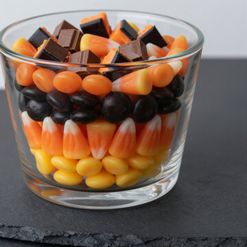 colorful halloween candy corn in glass bowl with chocolate pieces for festive autumn celebration