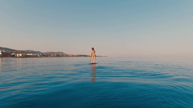 V&iacute;deo de una persona practicando paddle surf en mar en calma, con costa lejana y luz suave.