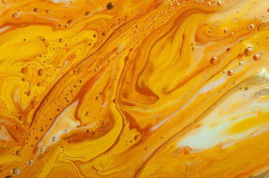 Swirls of orange and yellow colors mix together in a vibrant display of liquid art