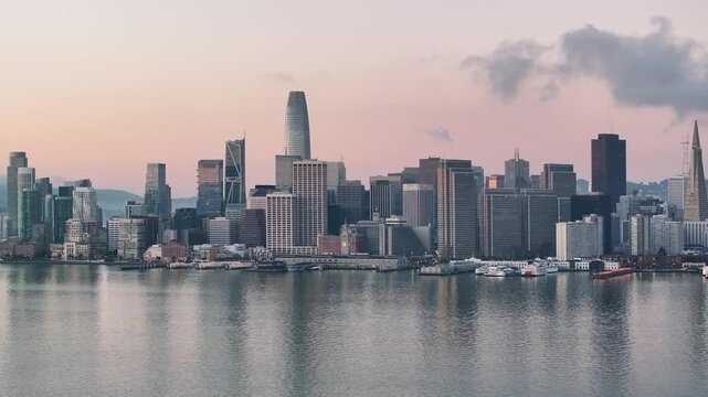 San Francisco skyline at sunrise featuring Salesforce Tower and waterfront harbor with soft morning light.
