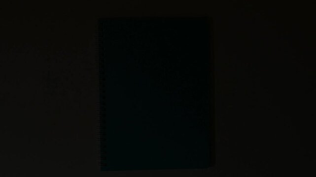 Top view of a teal spiral notebook on a white surface with light fade transition