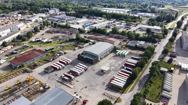 Aerial view of an industrial zone showcasing transport enterprises and factories, highlighting the layout of buildings, vehicles, and equipment in a bustling commercial area
