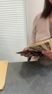 財布からお金を出して渡す女性