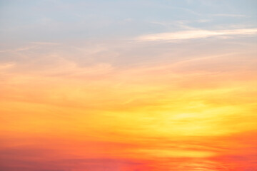 Fototapeta premium Beautiful sunrise sky with vibrant gradient orange and gold colors and soft blue, Clear atmosphere with wispy clouds. Peaceful, perfect for background and copy space, High resolution images