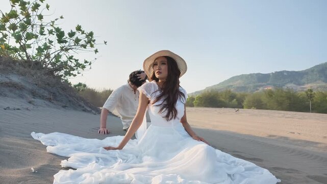 Indonesian southeast asian couple in love posing on sandy dunes during romantic pre-wedding photoshoot