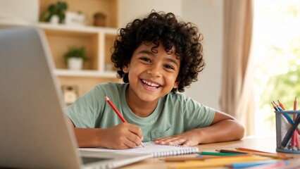 Obraz premium Happy young boy with curly hair sits at his desk writing in a notebook while using a laptop for schoolwork.