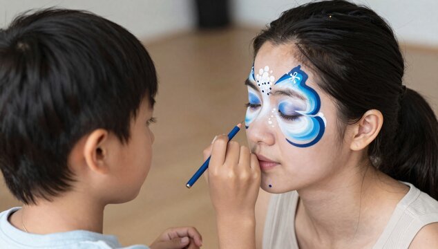 Little boy carefully paints a butterfly on the face of a dark-haired young woman