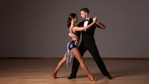 Elegant couple performing the tango in a studio with a wood floor and gray wall