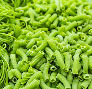 Background of colorful pasta texture close-up. Assortment of green macaroni
