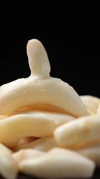 A pile of fresh peeled White Turmeric slowly rotating on a black background.