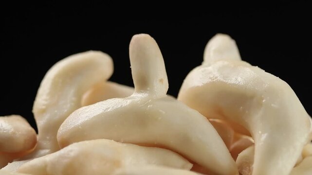 A pile of fresh peeled White Turmeric slowly rotating on a black background.