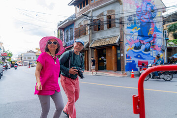 Couple walks on street in city with colorful mural and shops in the background during the day © Hip.hub