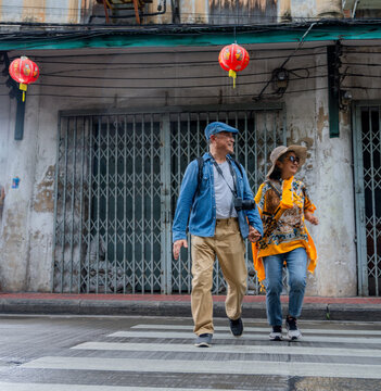 Couple walks hand in hand on a rainy street with red lanterns in a city