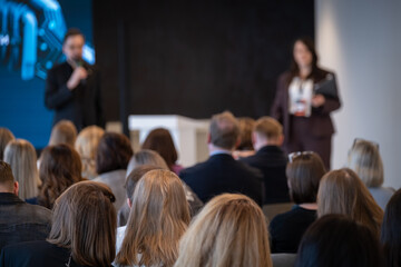 Obraz premium Conference audience listening to presenters in corporate seminar room, professional networking and learning atmosphere.