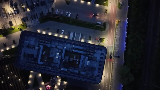 Aerial view of modern business center buildings illuminated at night, showcasing intricate architectural designs and surrounding landscaped areas with vibrant lighting and pathways