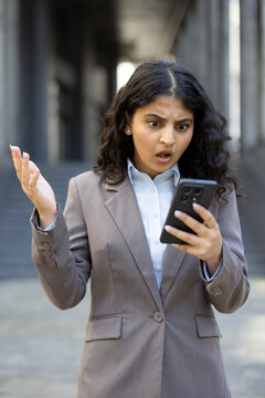 Businesswoman reacting with shock and frustration to smartphone news