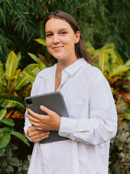 Young woman holding tablet device in tropical garden