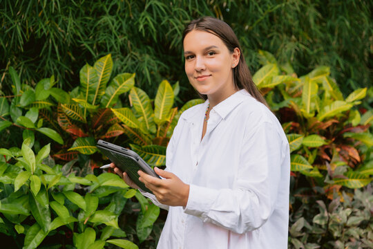 Woman with tablet outdoors surrounded by tropical plants