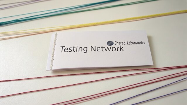 Business Card for Testing Network in Shared Laboratories with Colorful Threads Background on a White Surface