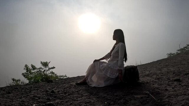 An introverted Asian woman takes a solo trip to Mount Kelud early in the morning while it is still quiet and deserted.