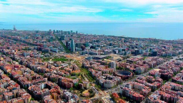 Aerial view of Barcelona, Spain, with the Torre Glories tower, Placa de les Glories works, the Monumental bullring, Poblenou office district, Eixample blocks and the Mediterranean Sea.