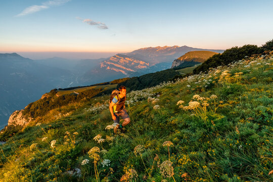 Outdoor adventure hiker walking through a wildflower meadow at sunset, capturing mountain exploration, Corno della Paura, Monte Baldo Natural Park, Brentonico, Trentino, Italy.