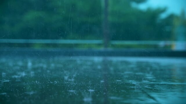 Slow motion close up of raindrops splashing on wet ground during a tropical storm