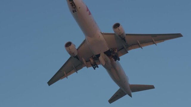 Wide shot of a super low flying airplane gradually climbing altitude at sunset, moving higher and farther into the sky during nighttime conditions.
