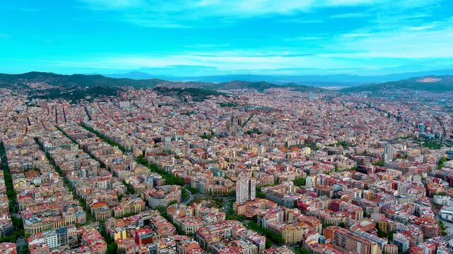 Aerial view of the Eixample district grid in Barcelona, Spain, with octagonal residential blocks, tree lined avenues, the Sagrada Familia basilica and Collserola hills on the horizon.
