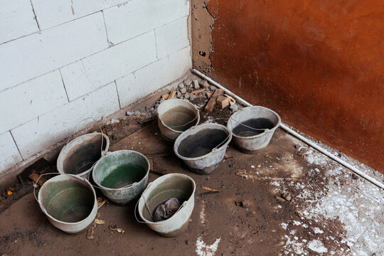 Dirty plastic cement buckets on a messy muddy floor at a construction site