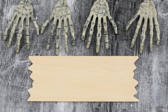 Two pairs of skeleton hands on with a sign weathered wood