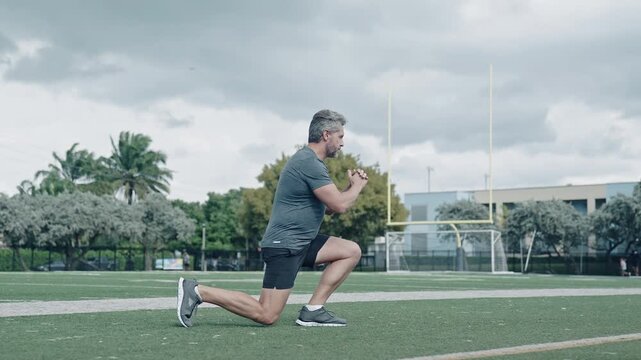 Active man exercising outdoor. Exercising and warming up. Senior man training leg muscle doing lunges exercise. Man in fitness do lunge exercising outdoor. Healthy activity